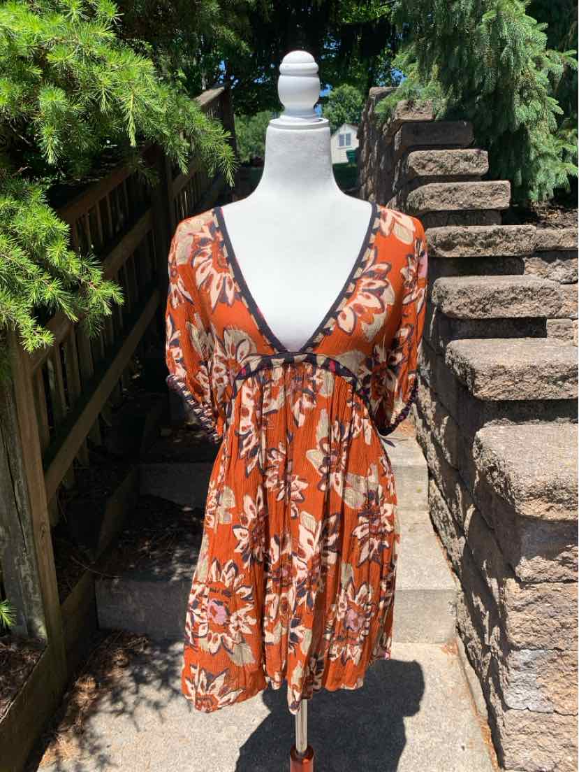 Orange floral patterned dress with V-neck, short sleeves, and empire waist on mannequin outdoors.