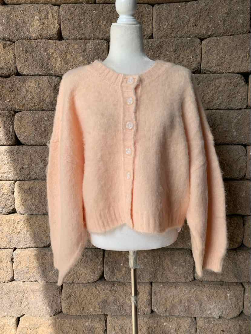 Peach fuzzy knit cardigan with a round neckline, button front, and cropped, boxy fit.