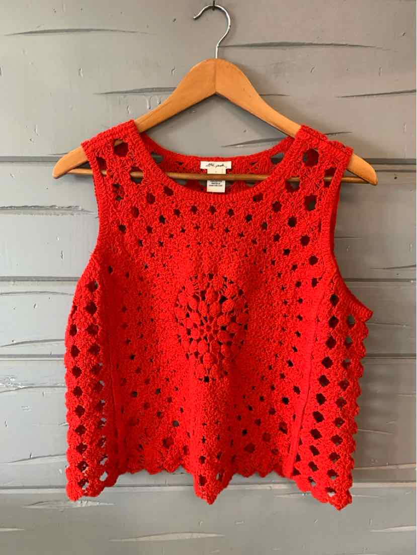 Bright pink sleeveless crochet top with openwork pattern and scalloped hem on wooden hanger.