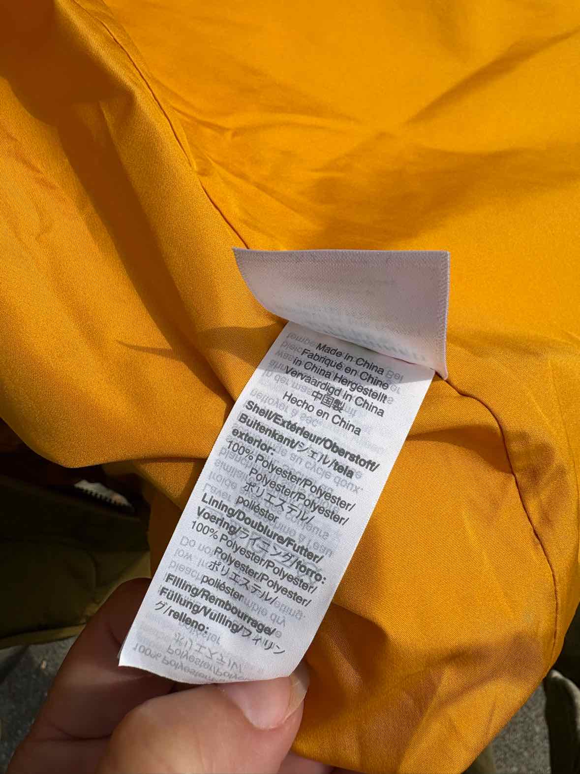 Mustard yellow J.Crew garment with a white care label attached to the fabric.