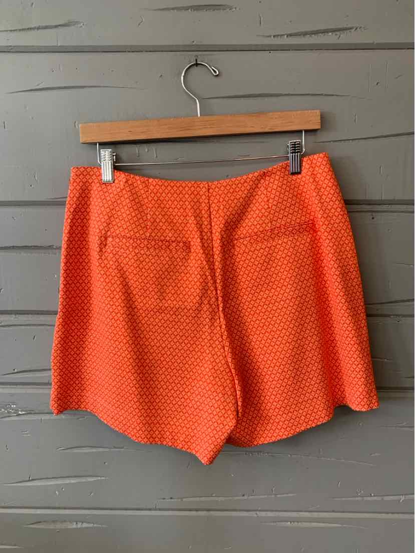 Orange textured high-waist shorts with subtle front pockets and a tailored fit on wooden hanger.