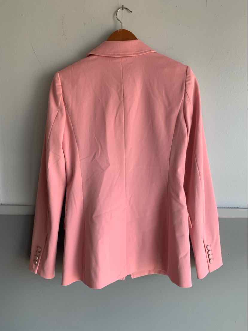 Soft pink tailored blazer in size 0 with structured shoulders and buttoned cuffs hanging on wooden hanger.