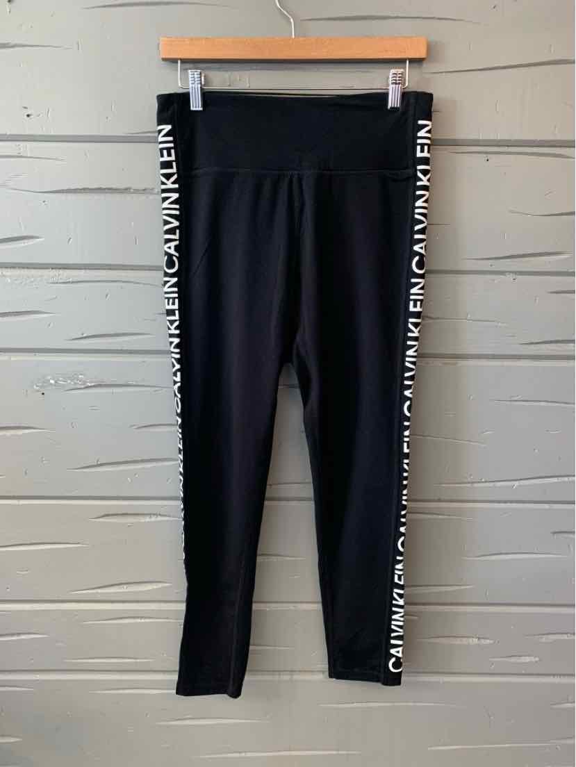 Black high-waisted leggings with white Calvin Klein logo stripes along the outer legs.