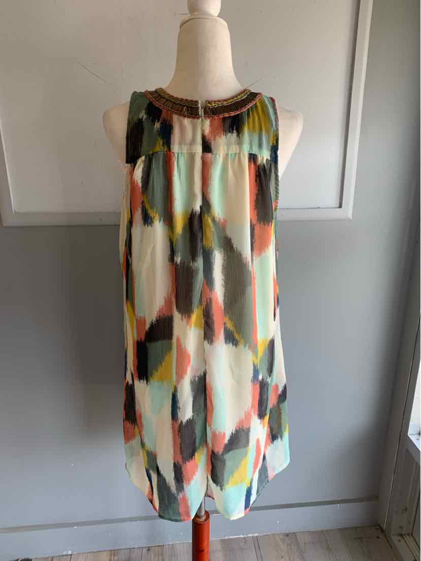 Sleeveless knee-length dress with watercolor geometric print in orange, teal, black, and beige, featuring a gathered yoke.