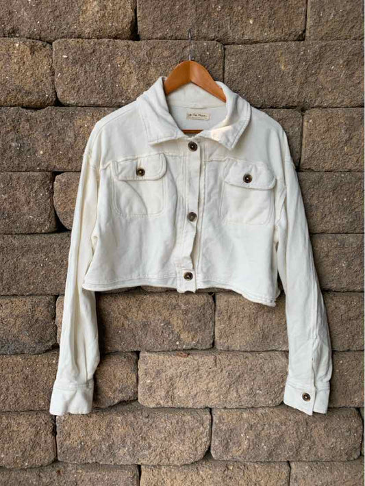 Cropped off-white denim jacket with button-front closure and flap chest pockets.