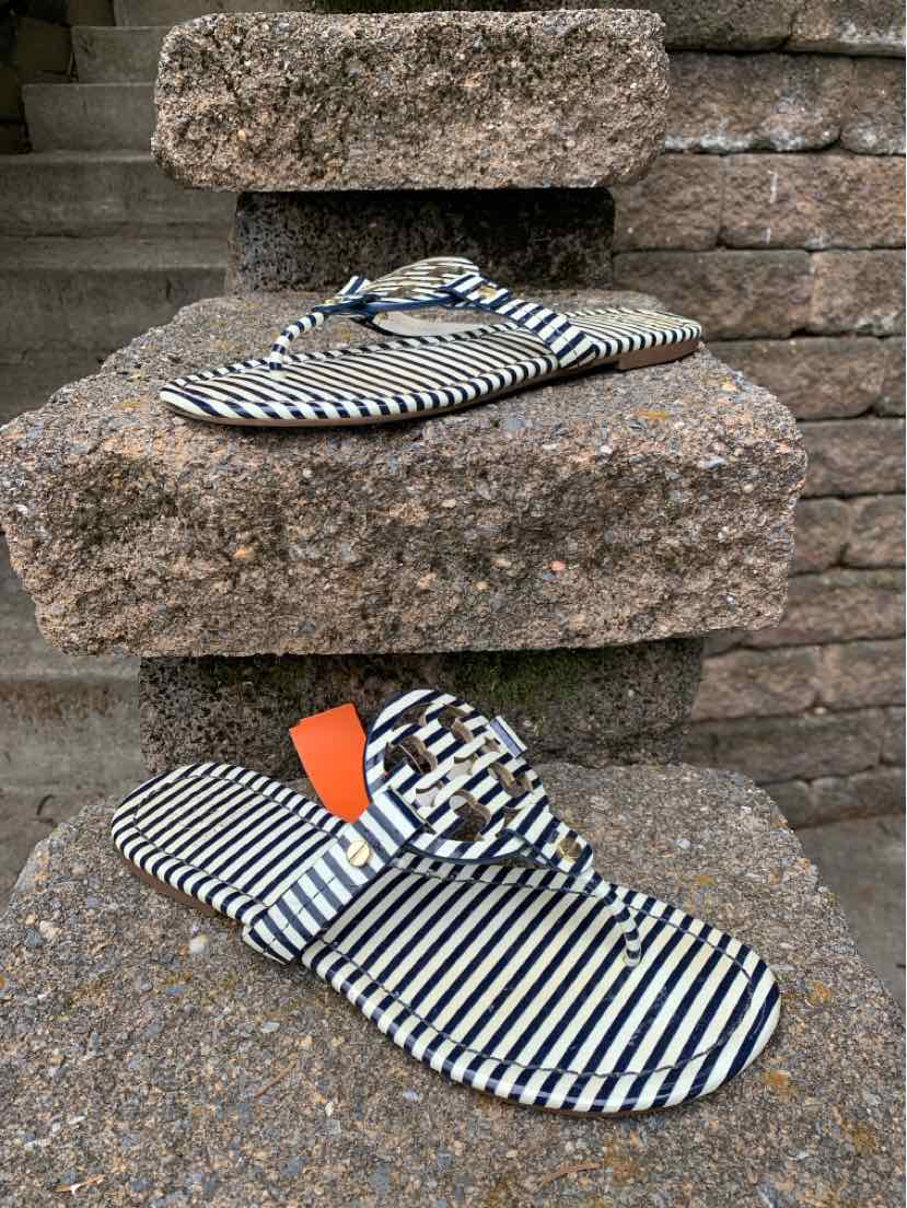 Black and white striped flat sandals with a thong strap and logo detail, size 7.5.