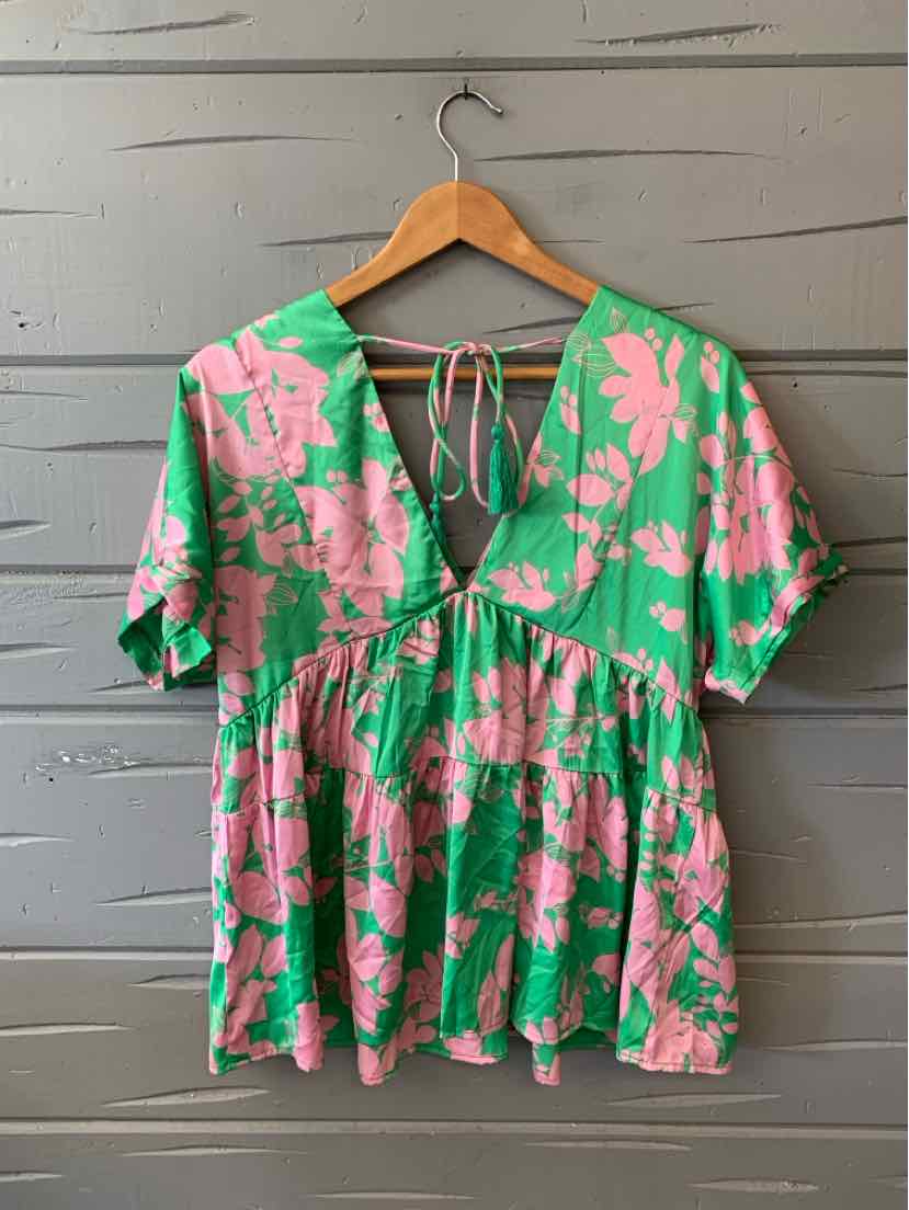 Green short-sleeve blouse with pink floral print, v-neck, and tiered ruffle hem.