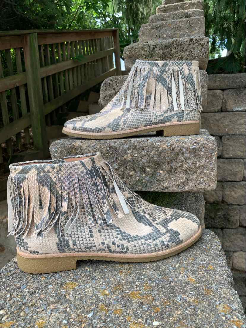 Tan snake print ankle boots with fringe details, flat sole, and side zipper closure.