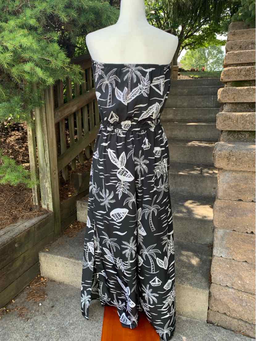 Black strapless maxi dress with white tropical leaf and flower print, flowing fabric.