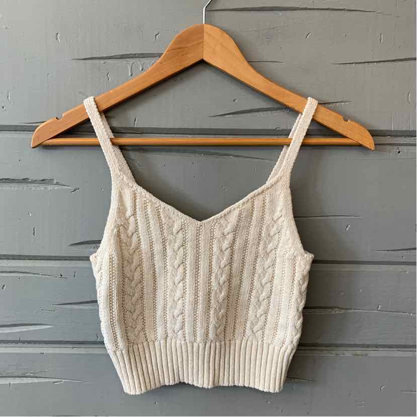 Tan cable knit cropped tank top with thin straps on wooden hanger.