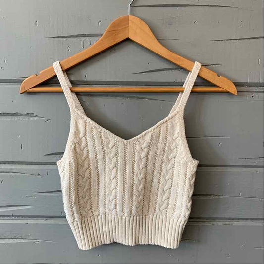 Tan cable knit cropped tank top with thin straps on wooden hanger.