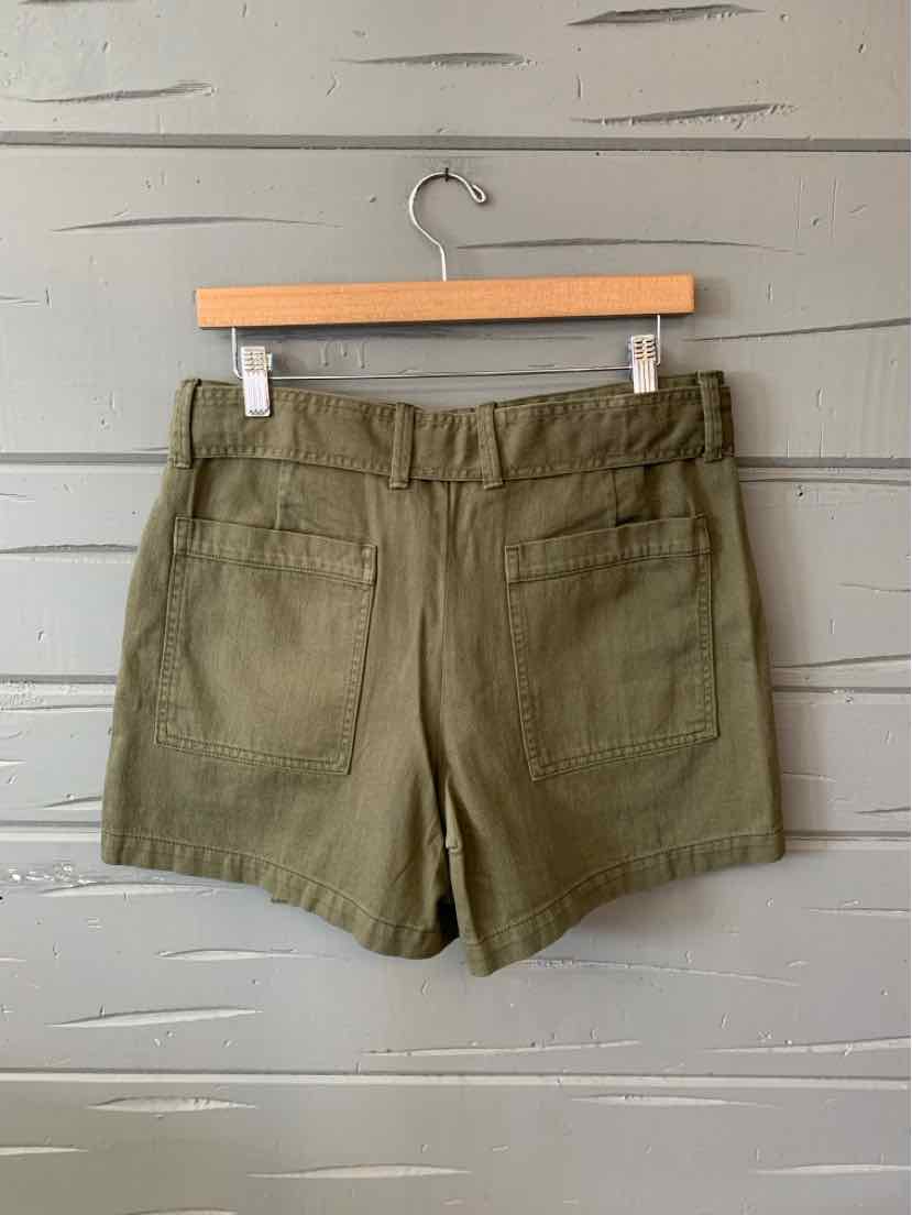 Olive green high-waist shorts with belt loops and back patch pockets hanging on wooden hanger.