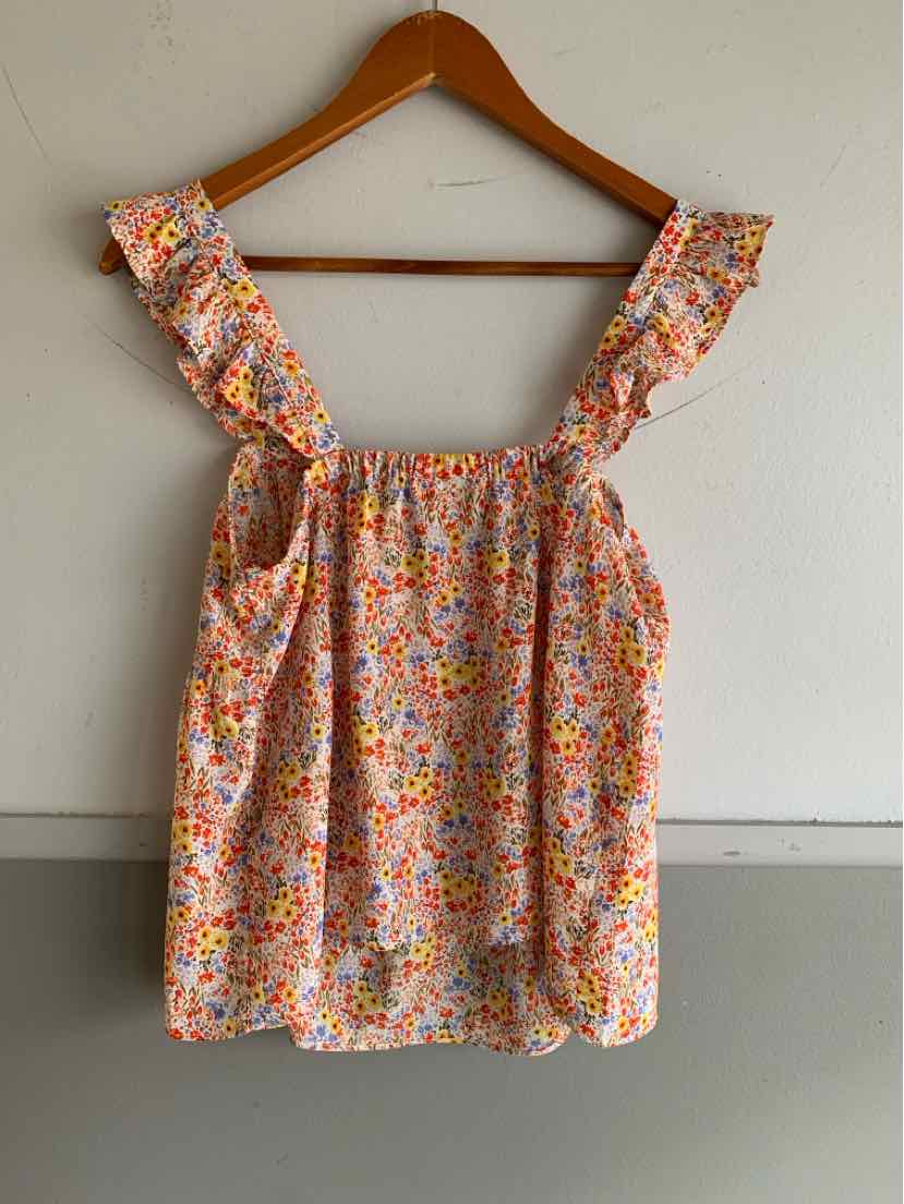 Sleeveless floral top with ruffled straps in orange, pink, and white tones hanging on wooden hanger.