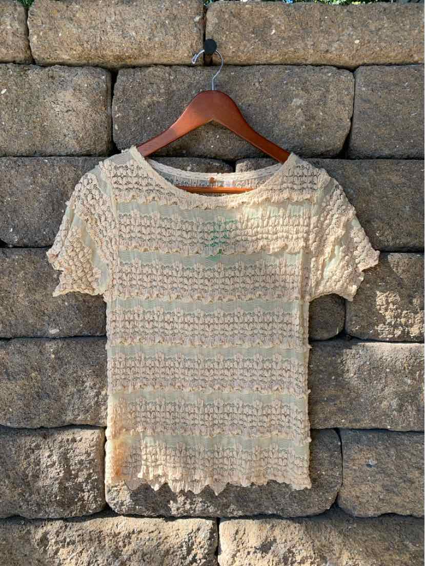 Tan lace short-sleeve top with scalloped edges and floral crochet pattern, size large.