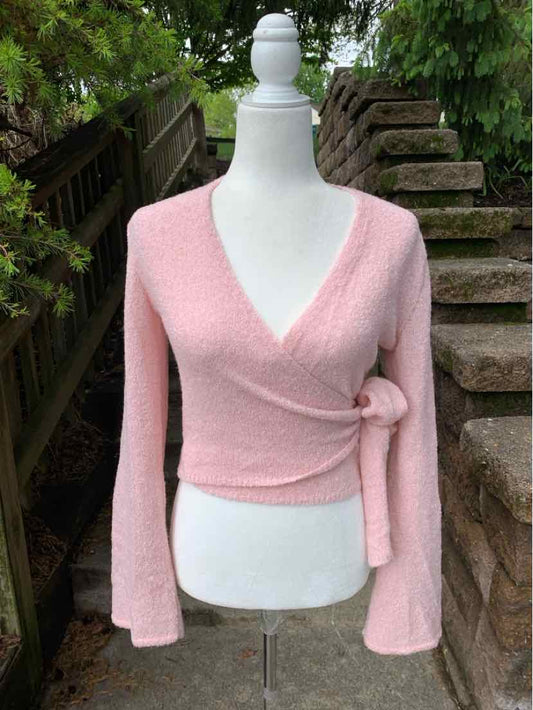 Light pink wrap-style knit sweater with long sleeves and side tie detail on mannequin.