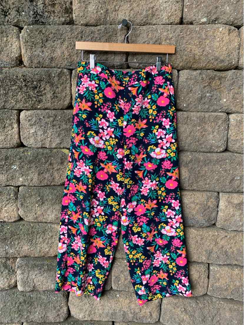 High-waisted cropped pants with a colorful floral print on dark navy fabric, button closure at waist.
