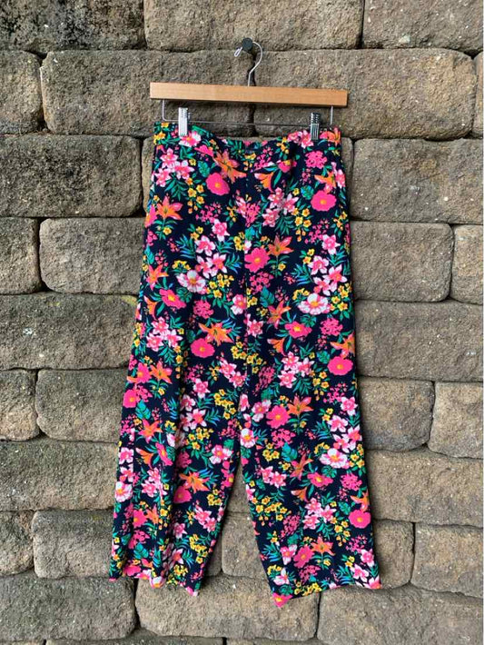 High-waisted cropped pants with a colorful floral print on dark navy fabric, button closure at waist.