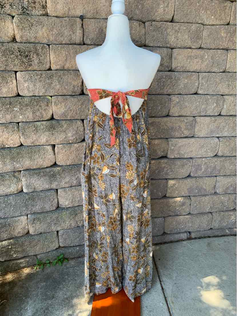 Back view of long floral dress with black, white, and orange pattern, featuring a tied bow at the upper back and sleeveless.