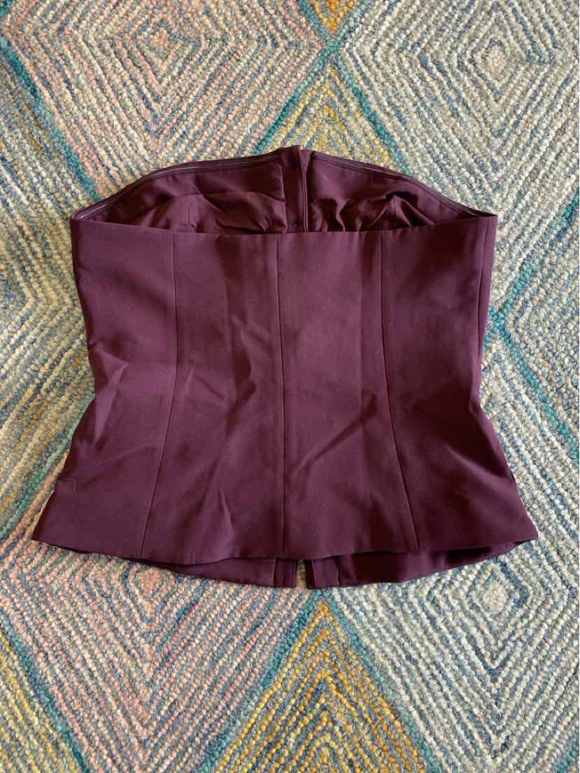 Deep burgundy strapless corset top with structured seams and slight peplum hem.