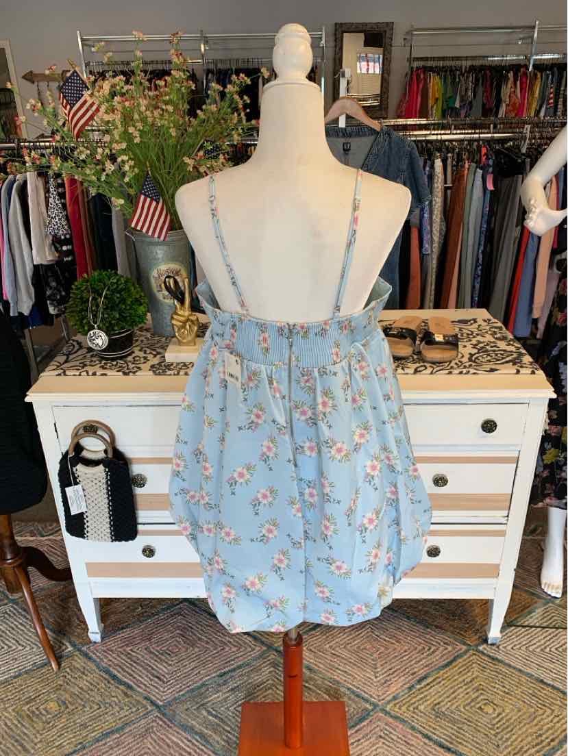 Light blue floral mini dress with thin adjustable straps and gathered back bodice on mannequin.