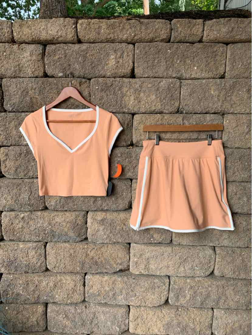 Peach-colored short-sleeve crop top and matching athletic shorts with white trim, soft fabric, casual activewear set.