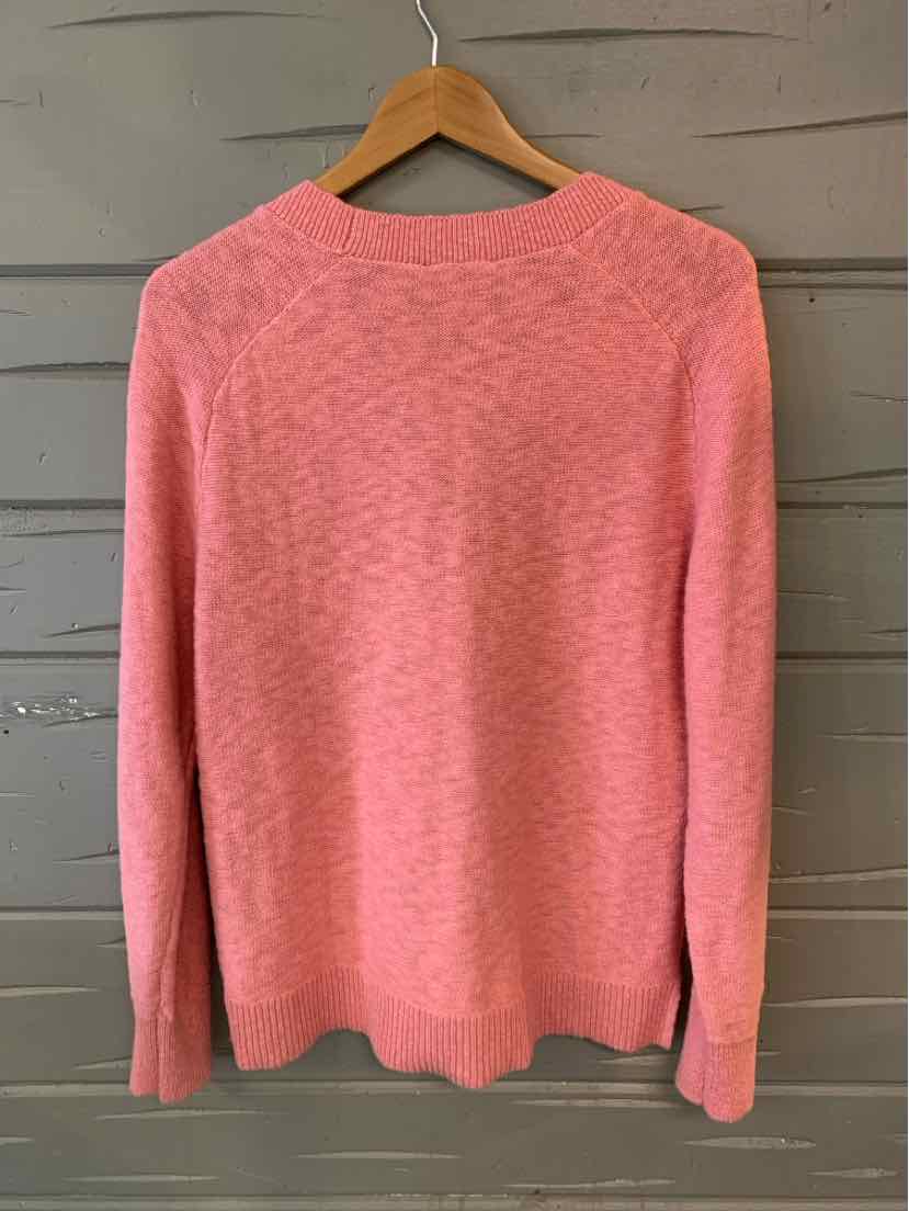 Pink medium knit sweater with long sleeves and crew neckline on wooden hanger.