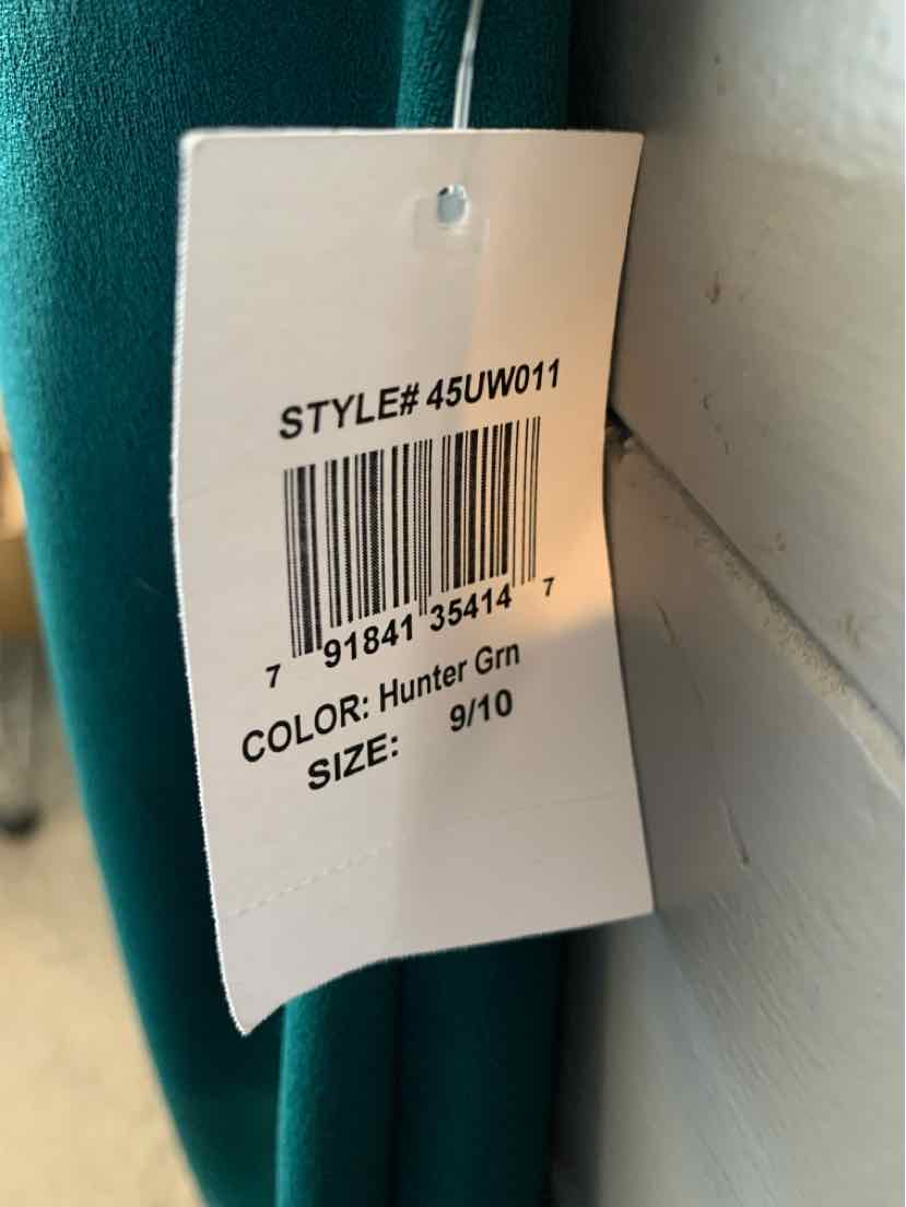 White clothing tag with black text showing style number, barcode, color "Hunter Grn," and size "9/10" against a hunter green .