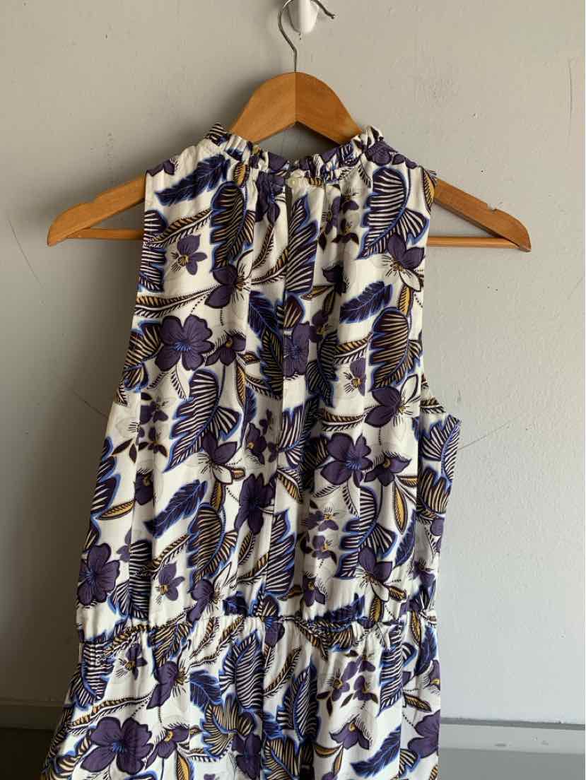 Sleeveless white blouse with blue and brown floral print and gathered neckline on wooden hanger.