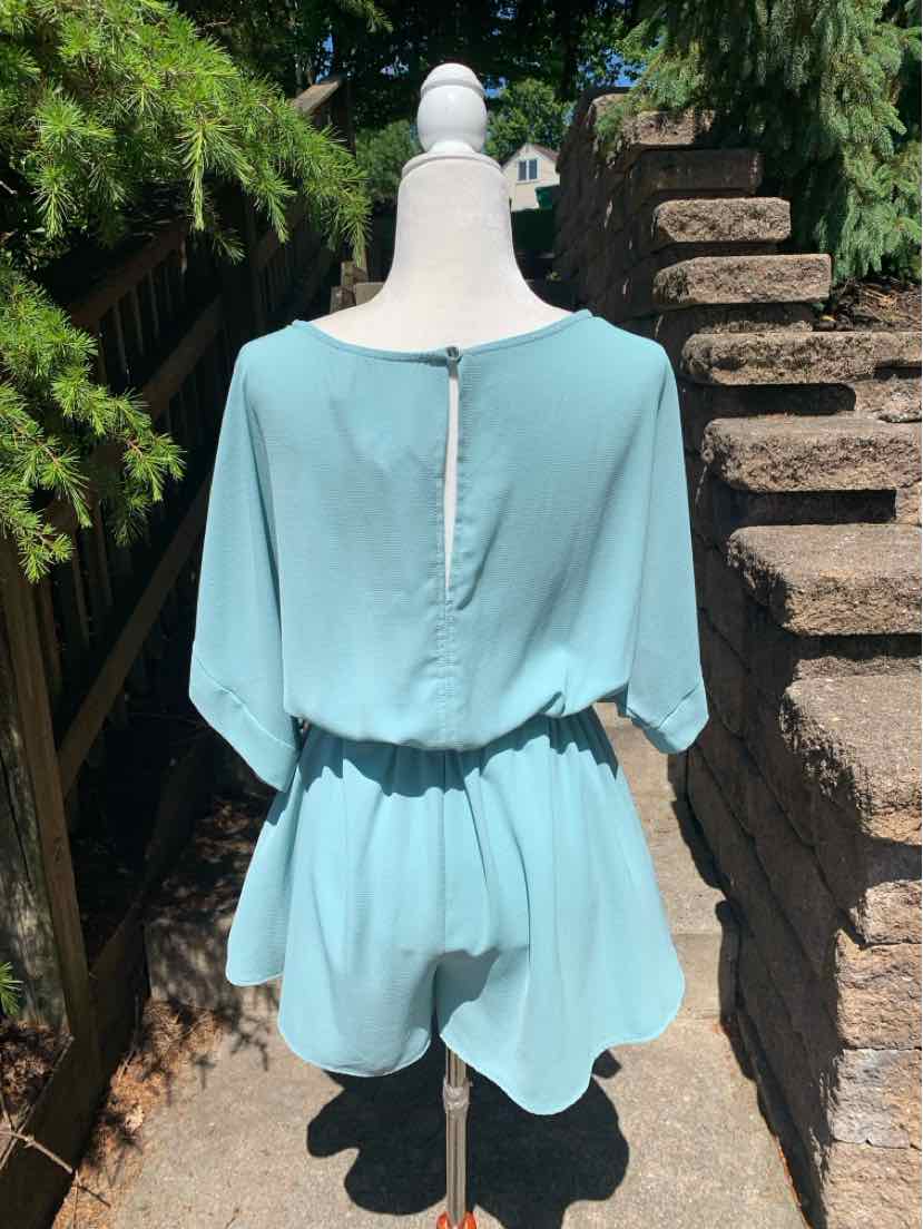 Teal short-sleeve romper with cinched waist and buttoned back keyhole closure on dress form.