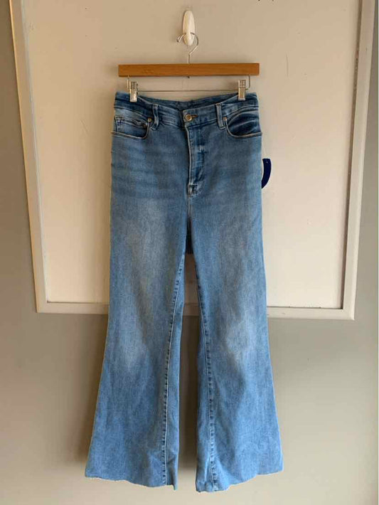 Light blue high-waist denim jeans with wide-leg cut and five-pocket styling hanging on wooden hanger.