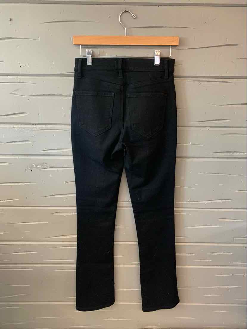 Black slim-fit denim jeans size 4 hanging on wooden hanger against gray textured wall.
