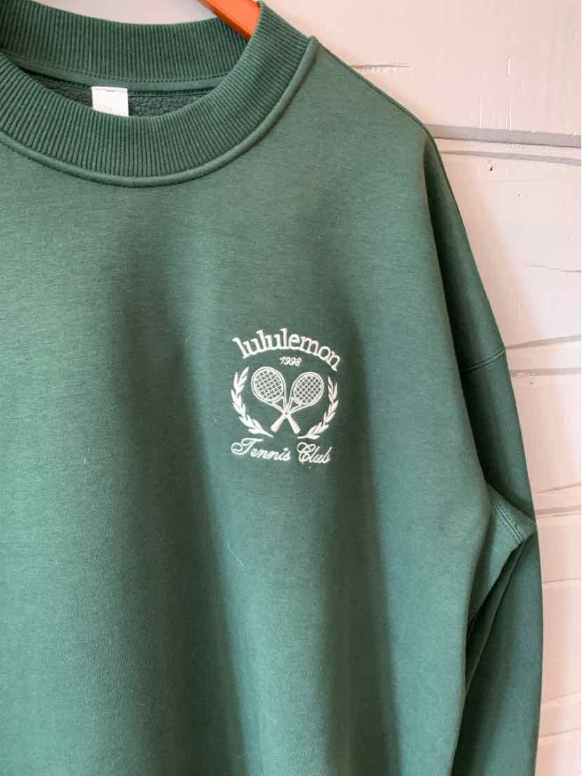 Green crewneck sweatshirt with white Lululemon tennis logo and text on chest.