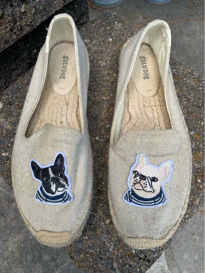 Pair of tan slip-on shoes with embroidered black and white dog faces on top, size 9.