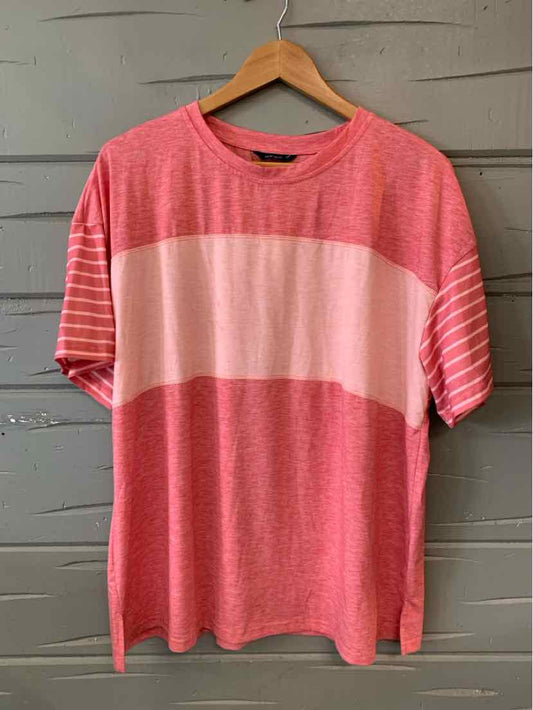 Red and pink color block oversized t-shirt with short sleeves and crew neck on wooden hanger.