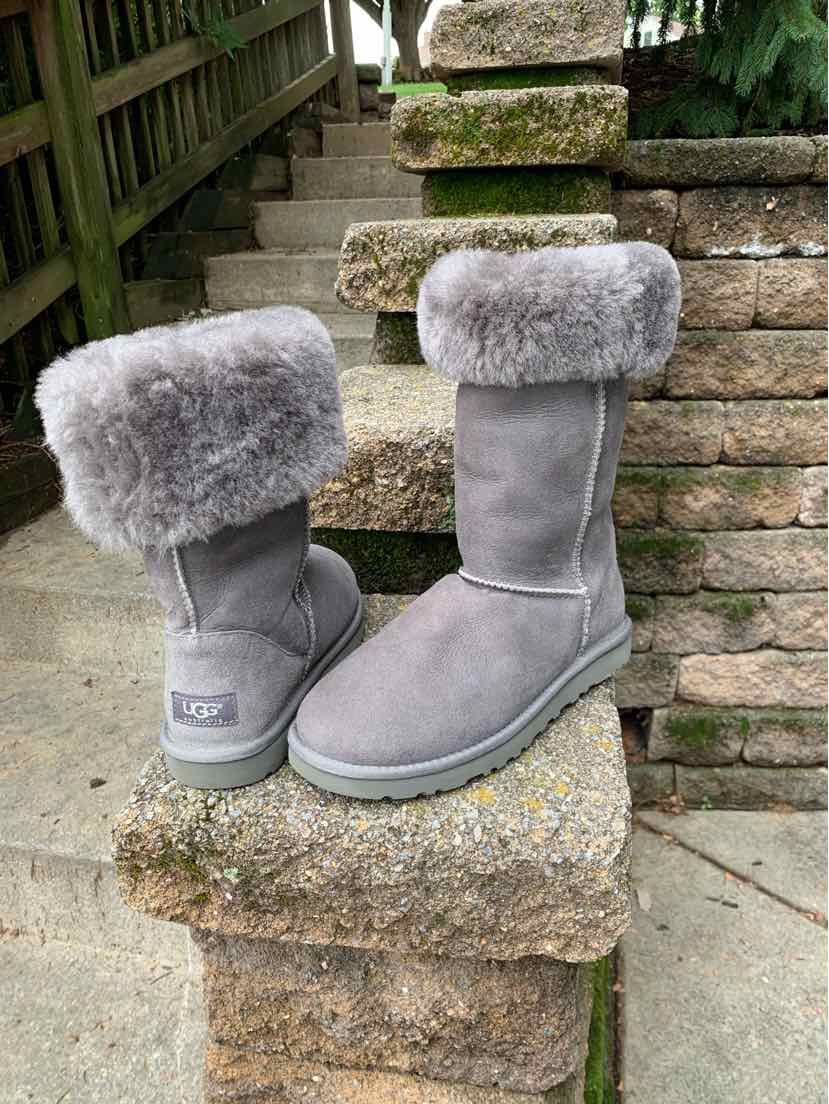 Gray suede mid-calf UGG boots with folded plush shearling collars and rubber soles, size 8.
