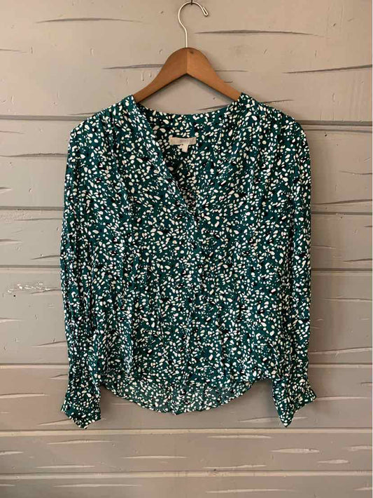 Green floral patterned long-sleeve blouse with button-down front and collar on wooden hanger.