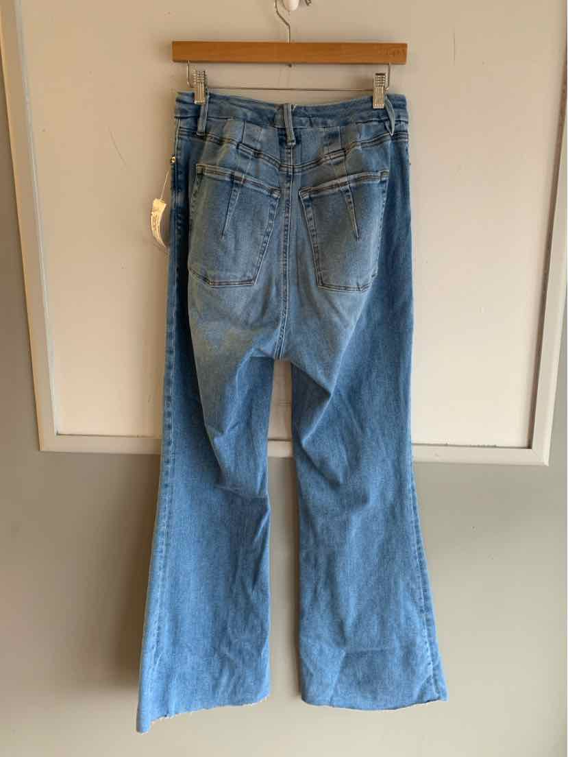 Light blue wide-leg denim jeans with back pockets and visible stitching hanging on wooden hanger.