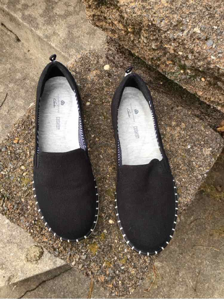 Black slip-on shoes with white stitching around the sole, size 6.5.