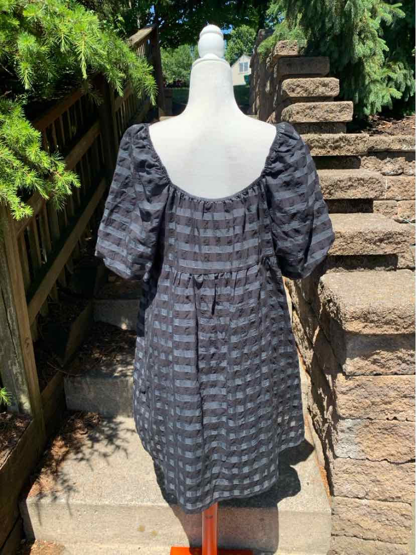 Black and gray striped dress with puffed short sleeves and a square neckline on a mannequin outdoors.