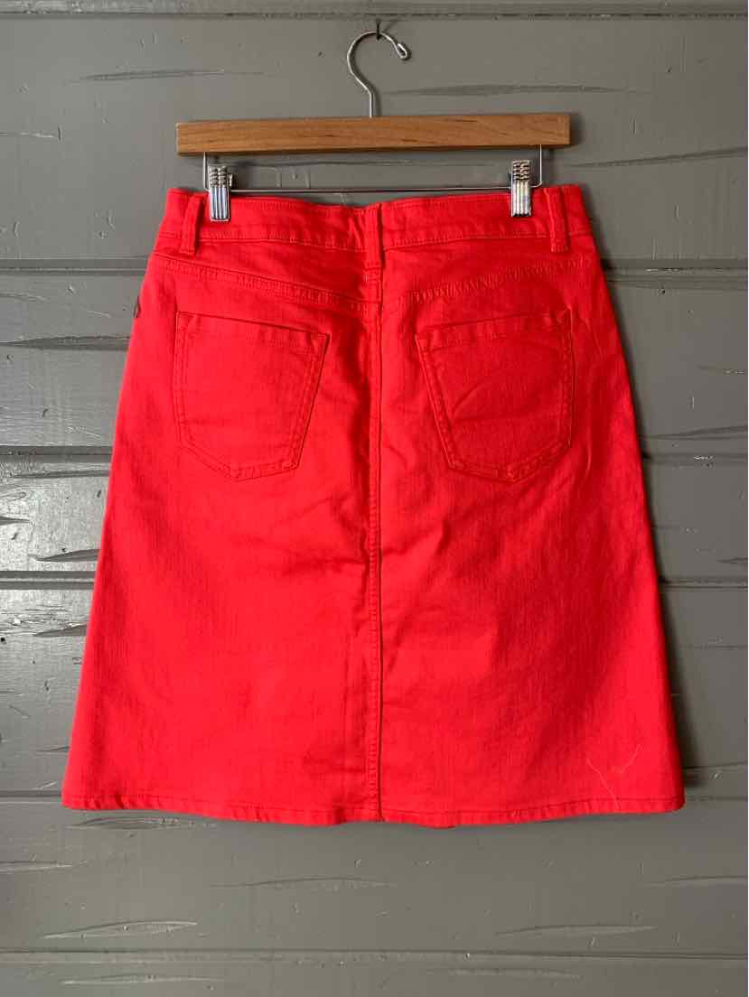 Red denim skirt with back pockets and belt loops, size 4, hanging on wooden hanger.