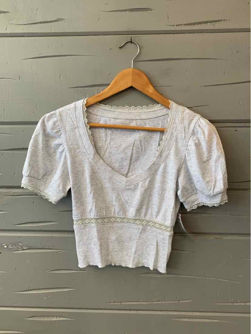 Light gray cropped knit top with short puff sleeves and deep scoop neckline.