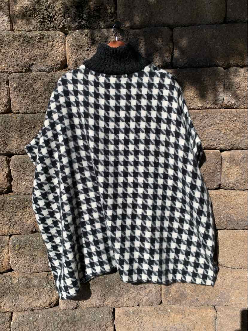 Black-and-white houndstooth poncho with a black ribbed turtleneck collar and draped sleeves.