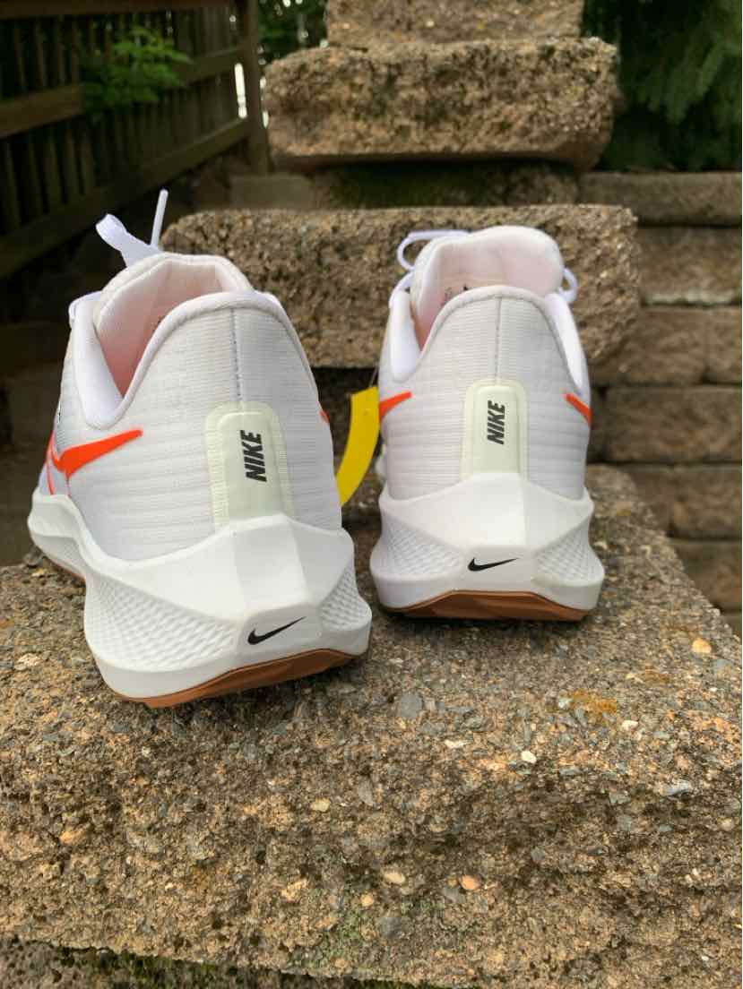 White Nike sneakers in size 8.5 with mesh upper, cushioned sole, and subtle orange accents seen from the back.