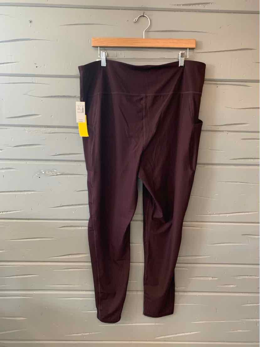 Plus-size burgundy straight-leg pants with tag on waistband hanging on wooden hanger.