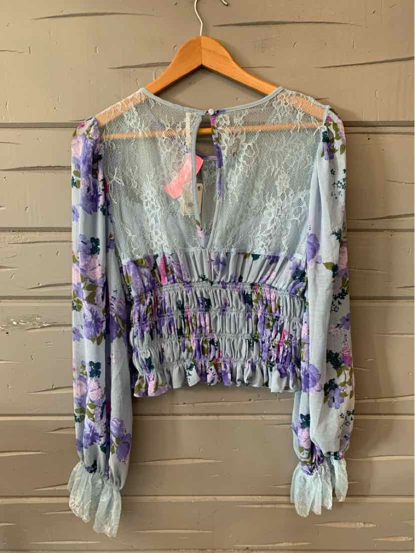 Sheer long-sleeve blouse with smocked waist and floral print in pastel purple and green tones.