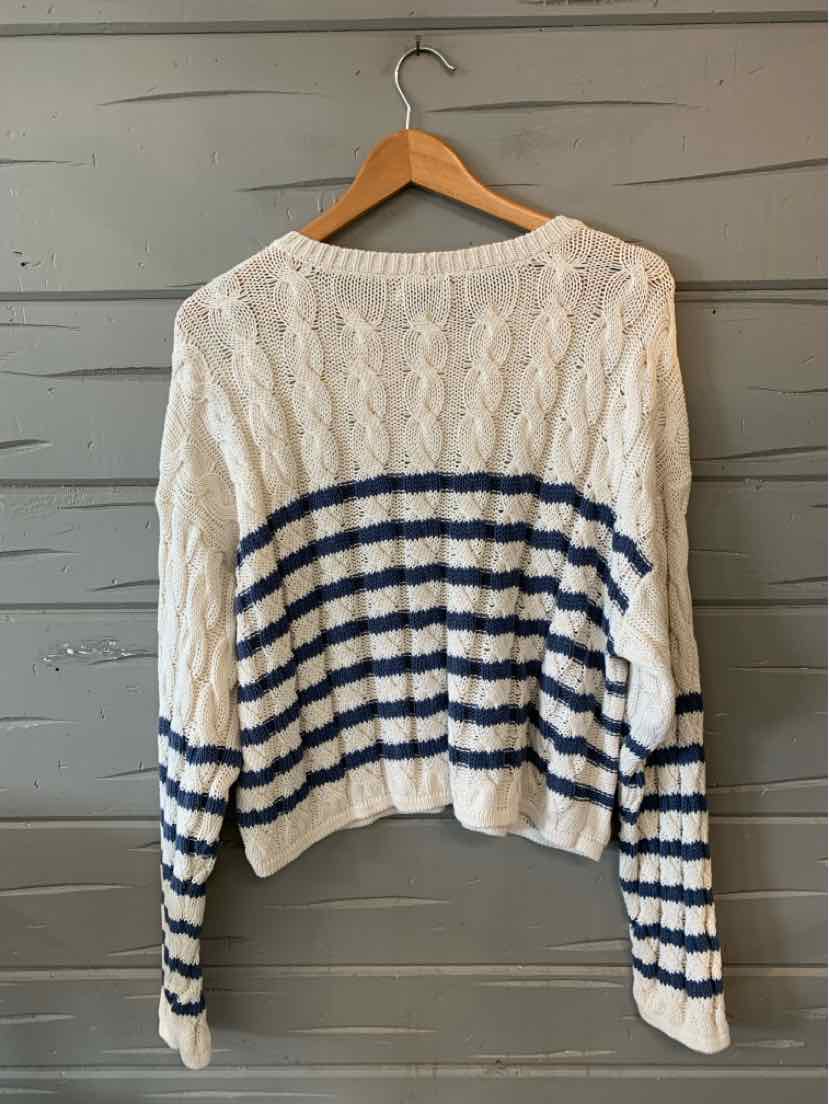 White knit sweater with navy horizontal stripes on lower half and sleeves, crew neckline, and ribbed hem and cuffs.