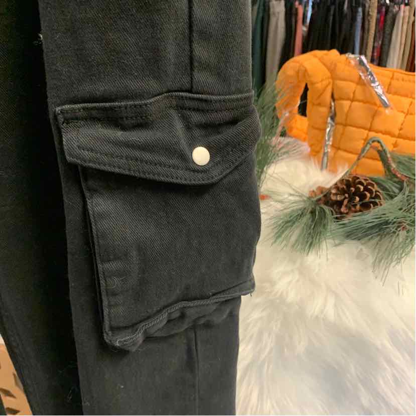 Black denim pants with flap cargo pocket and white button closure.