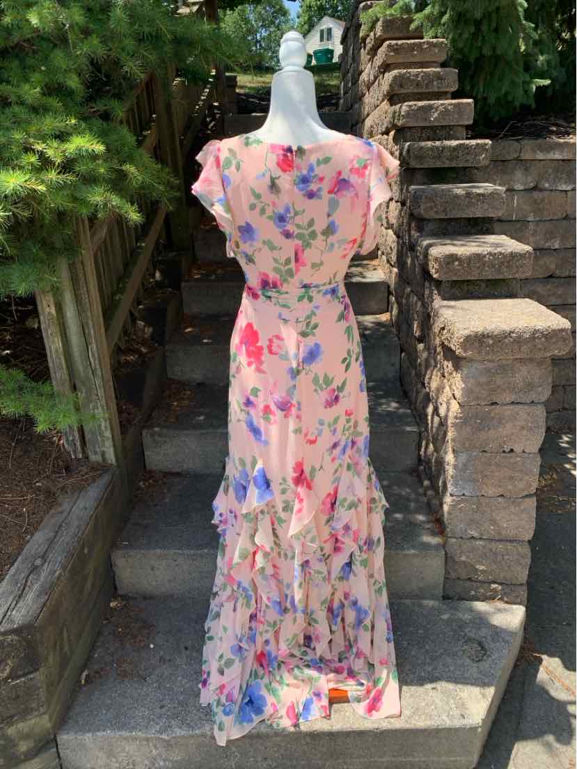 Pink floral maxi dress with cap sleeves and tiered ruffle skirt on mannequin outdoors.