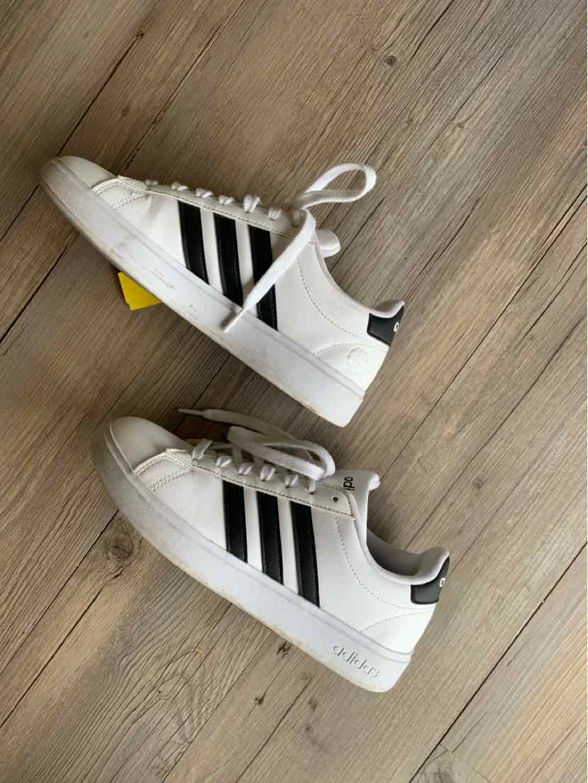 White Adidas sneakers with black stripes, lace-up design, and rubber sole, women’s size 7.5.