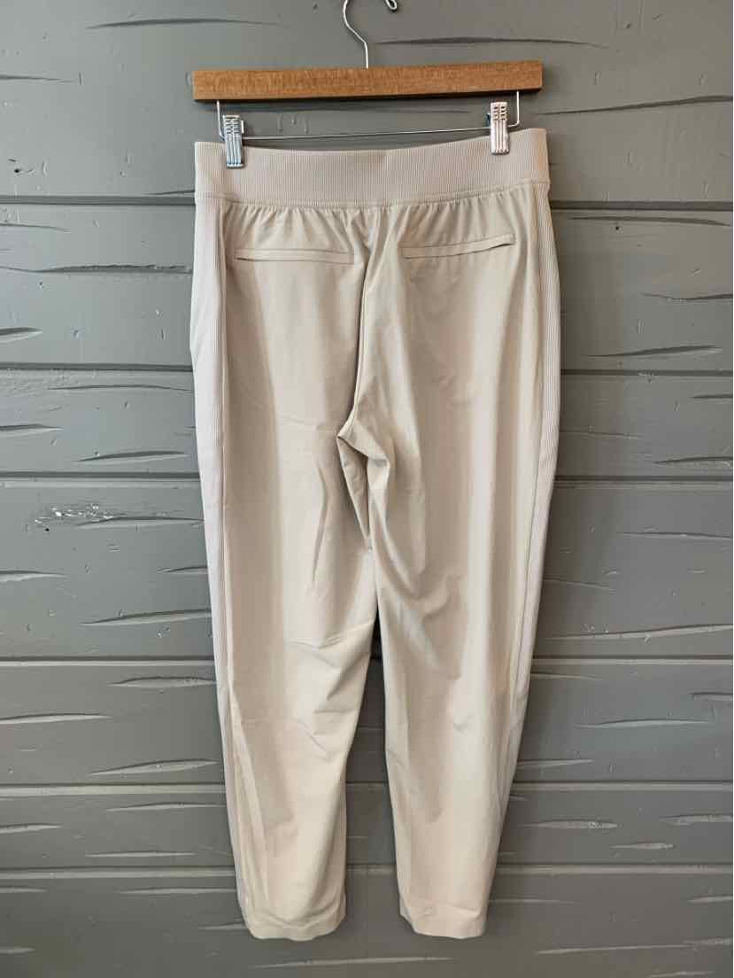 Tan tapered jogger pants with elastic waistband and two back welt pockets, size 6.